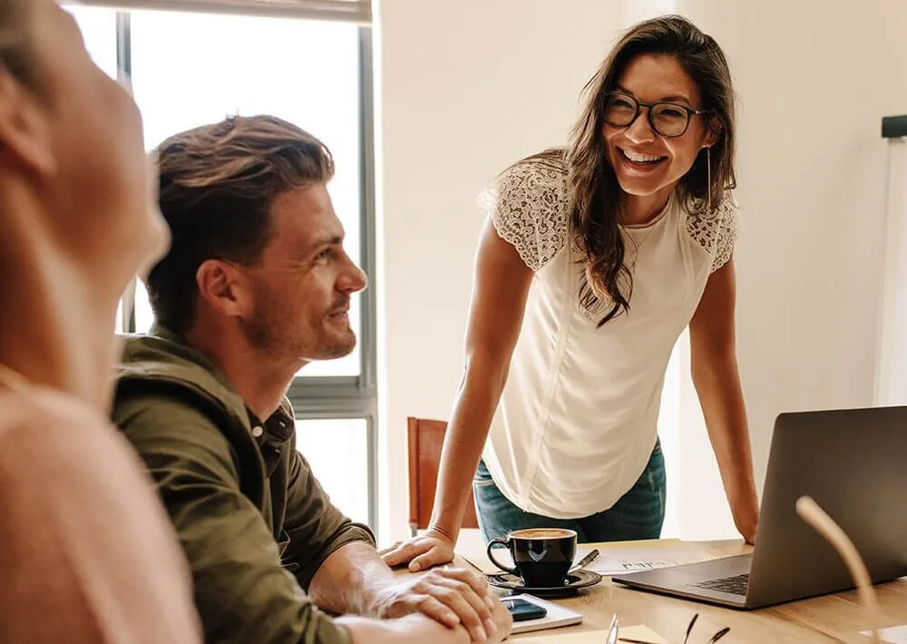 Photo: Small team gathered around a table discussing leadership development
